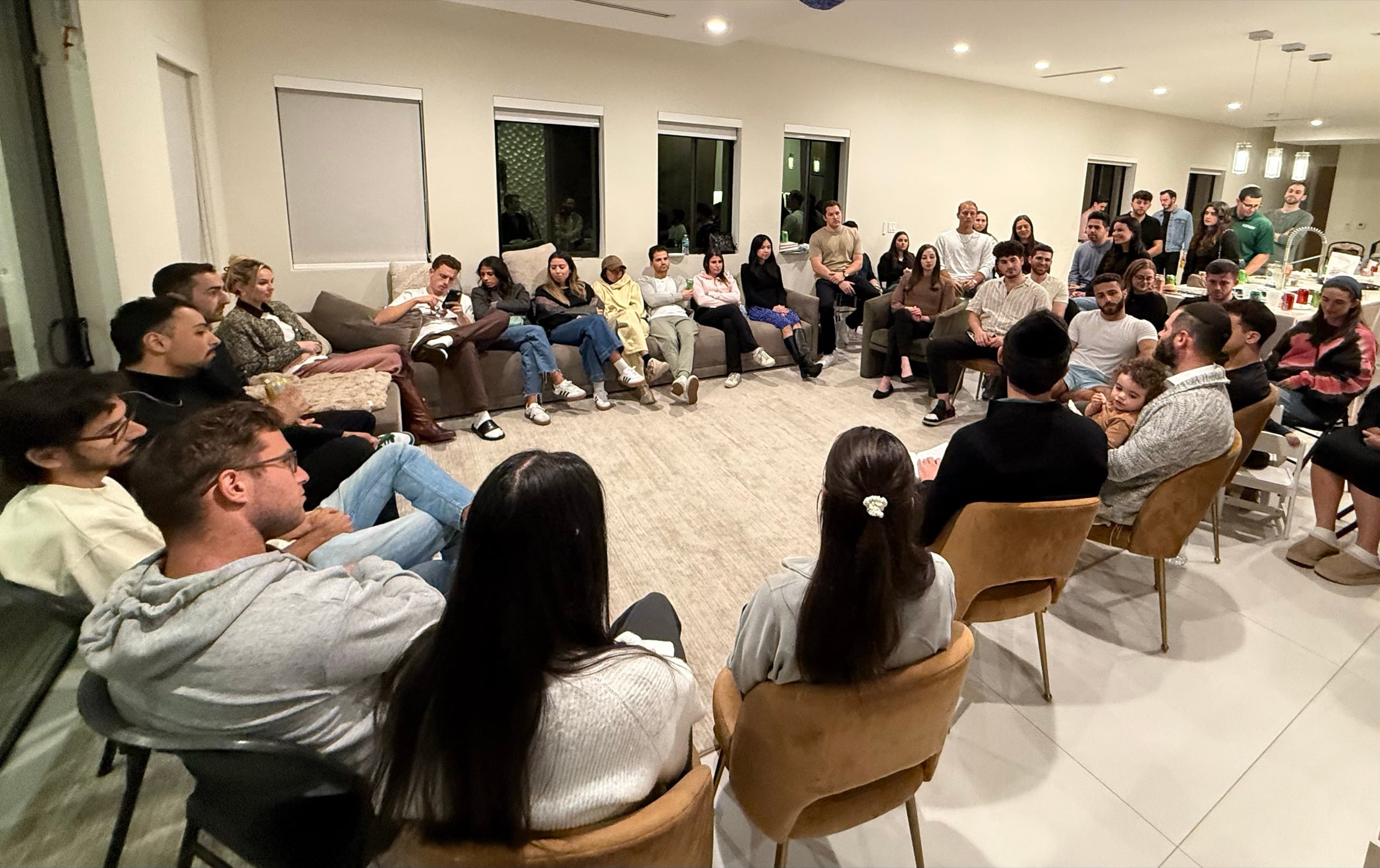 A packed living-room class, everyone in a circle